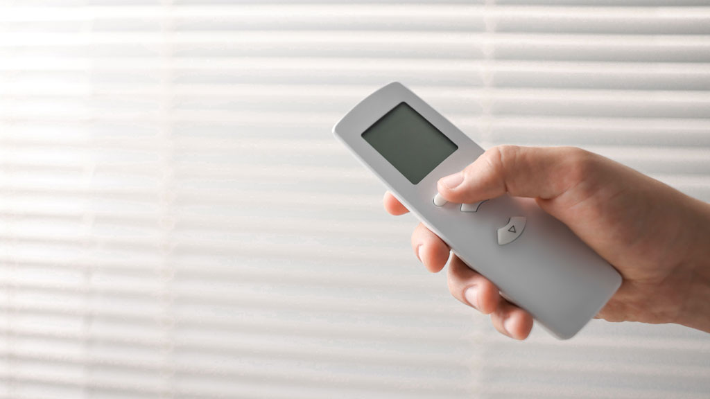 Personne utilisant une télécommande radio pour volet roulant dans un salon lumineux